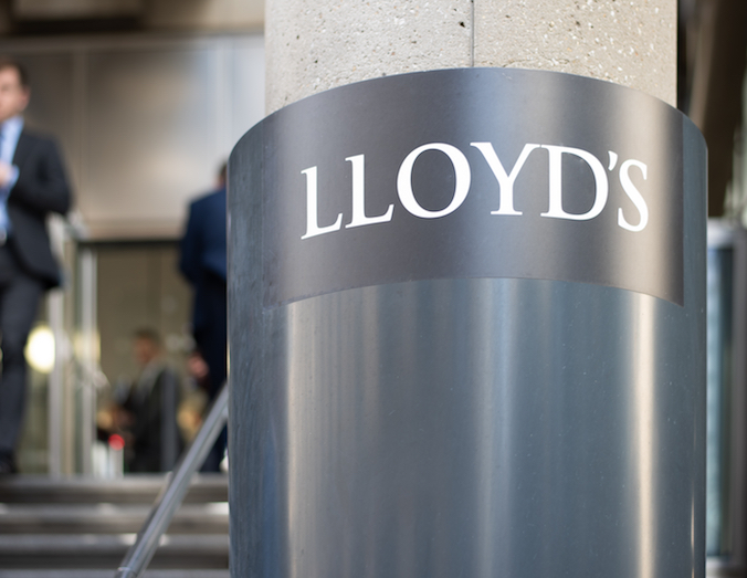 London, London/UK - April 10 2019: City worker in the background is seen leaving the Lloyds building. Sign for Lloyds is sharp, whereas city worker is blurred for effect.